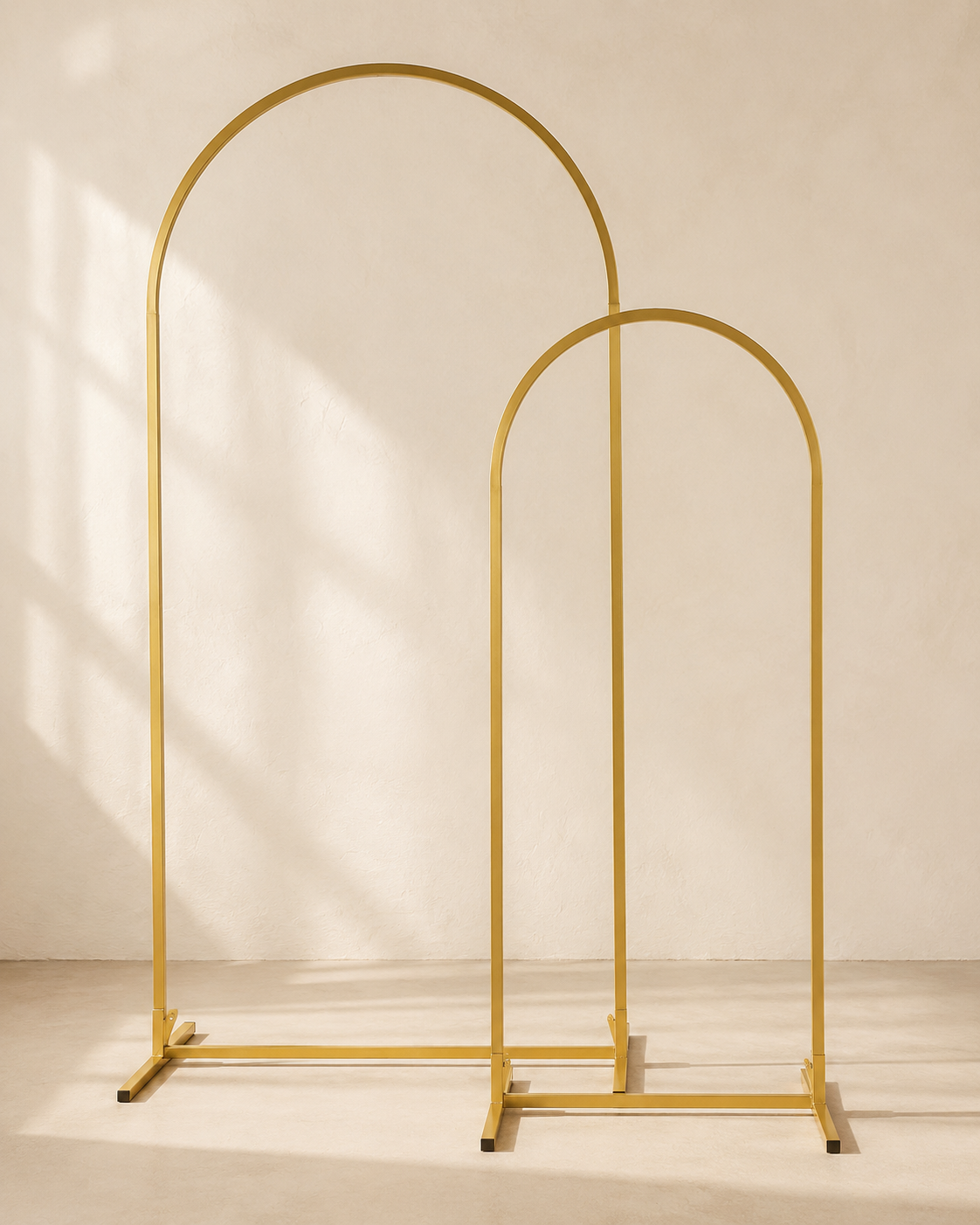 Two freestanding gold metal arch stands in different sizes