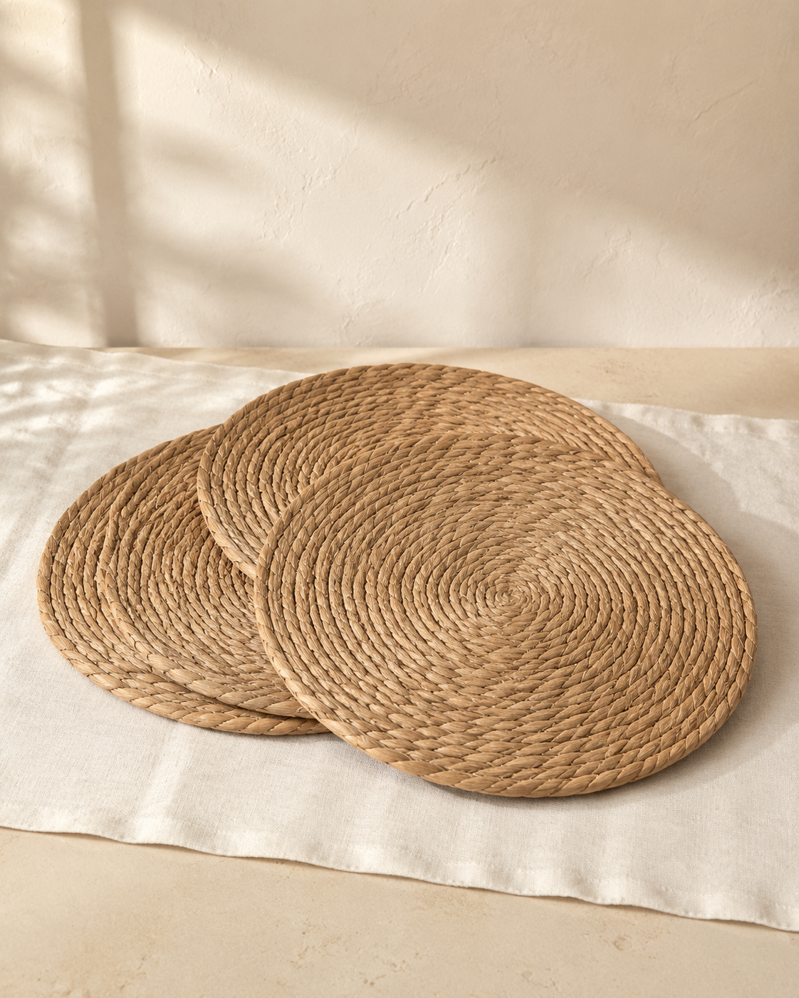 Three natural woven round placemats on a cream linen runner